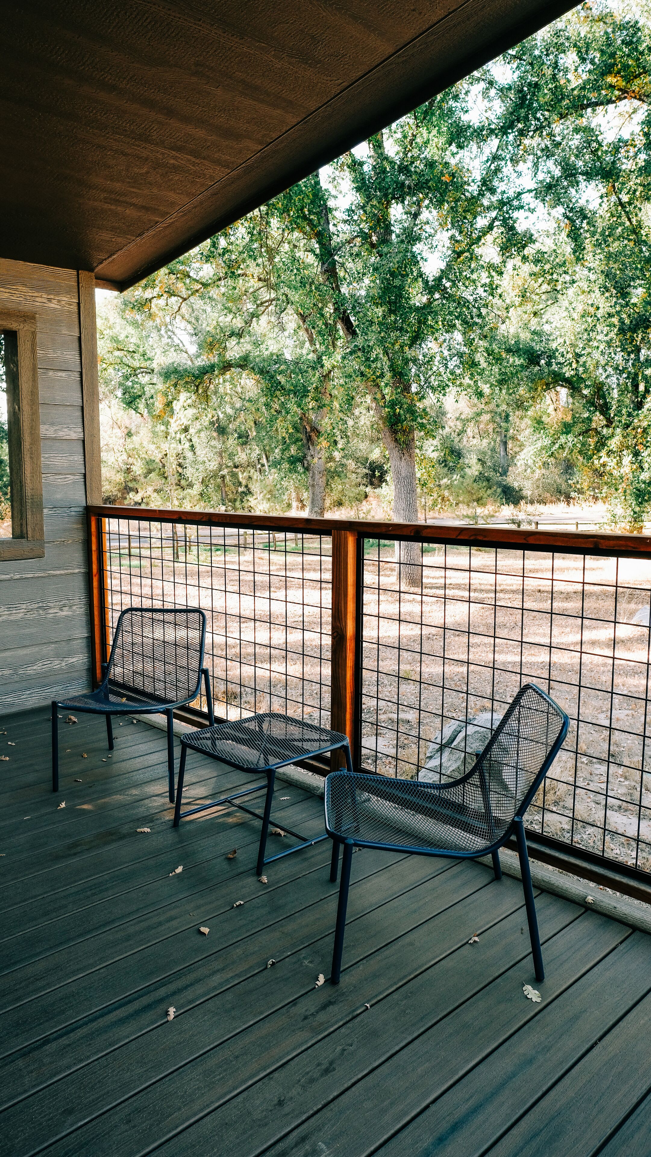 A covered outdoor seating area with metal chairs and a wooden deck.