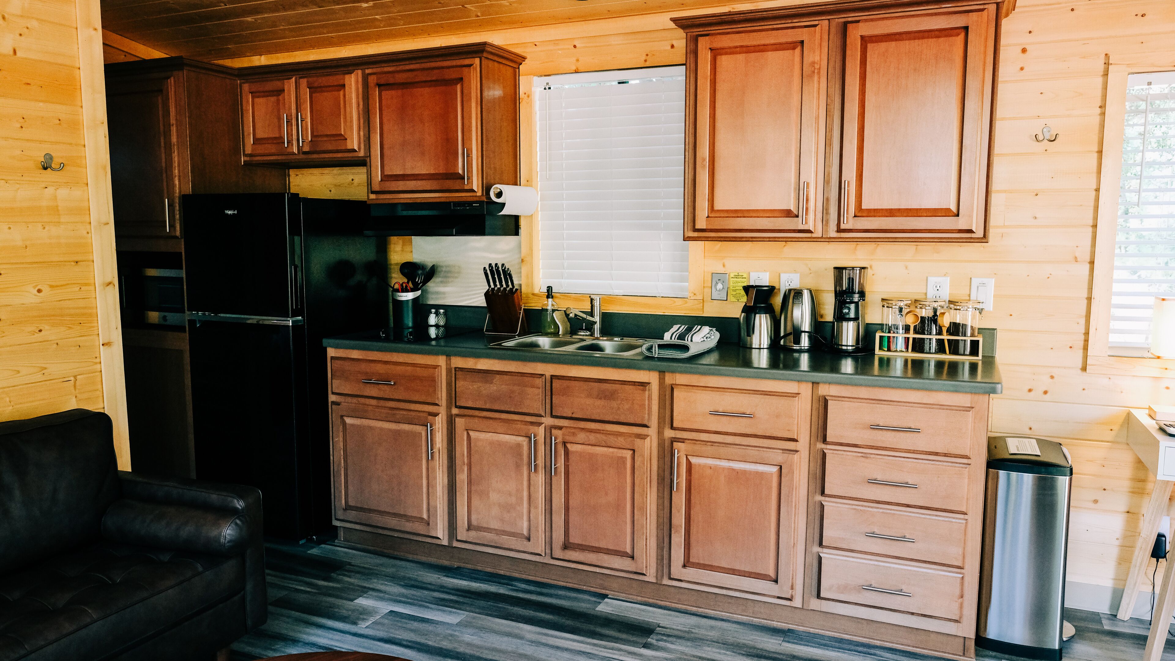 Una cocina con armarios de madera, un refrigerador de acero inoxidable, un lavaplatos y varios electrodomésticos.