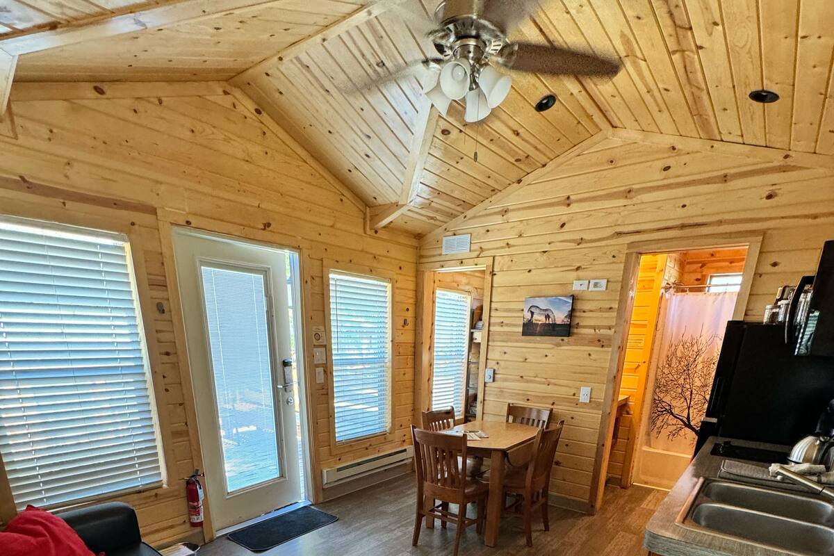 A wooden cabin interior with a dining area, kitchen, and living space.