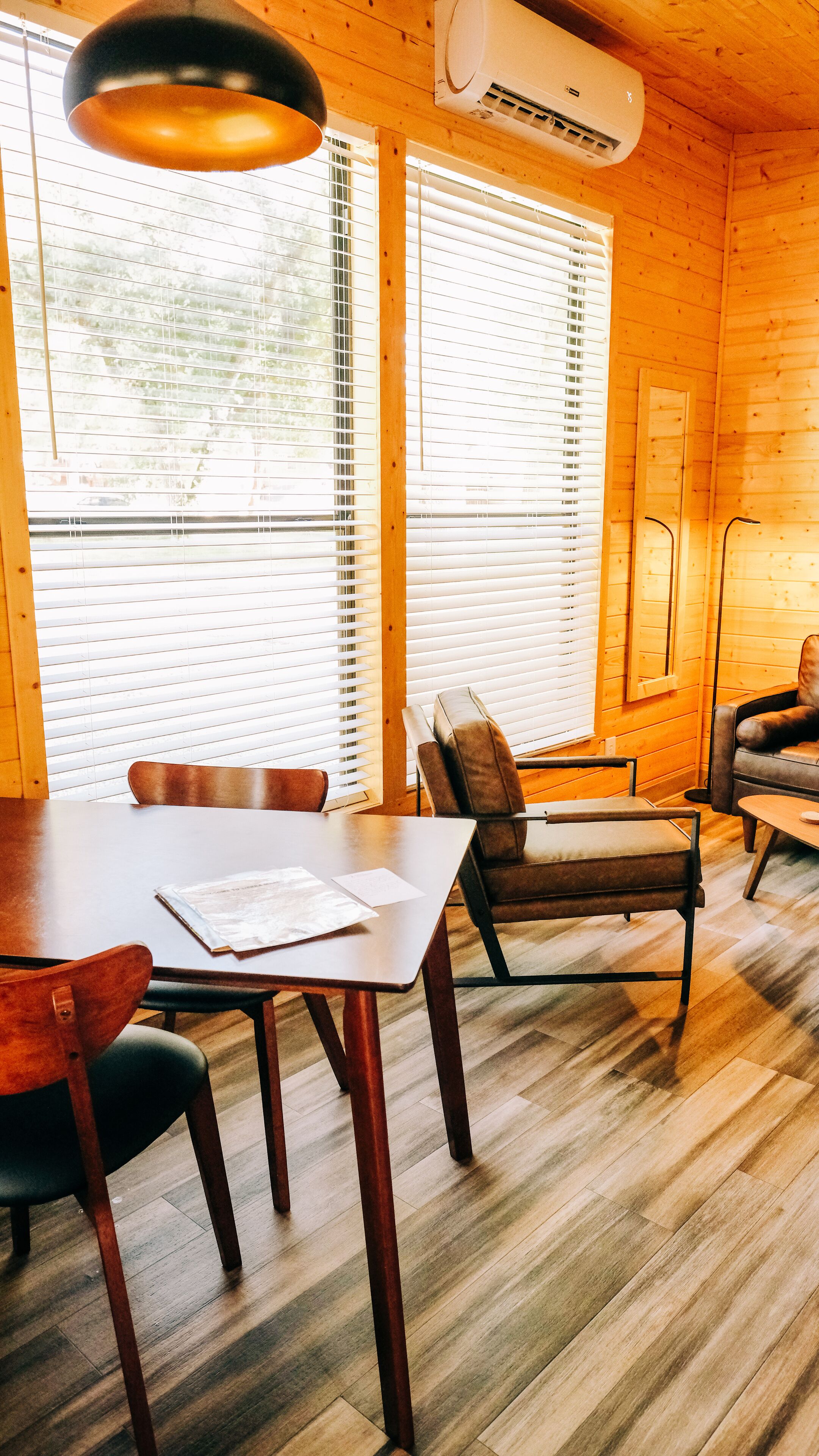 A wooden interior with a dining table, chairs, and a sofa.
