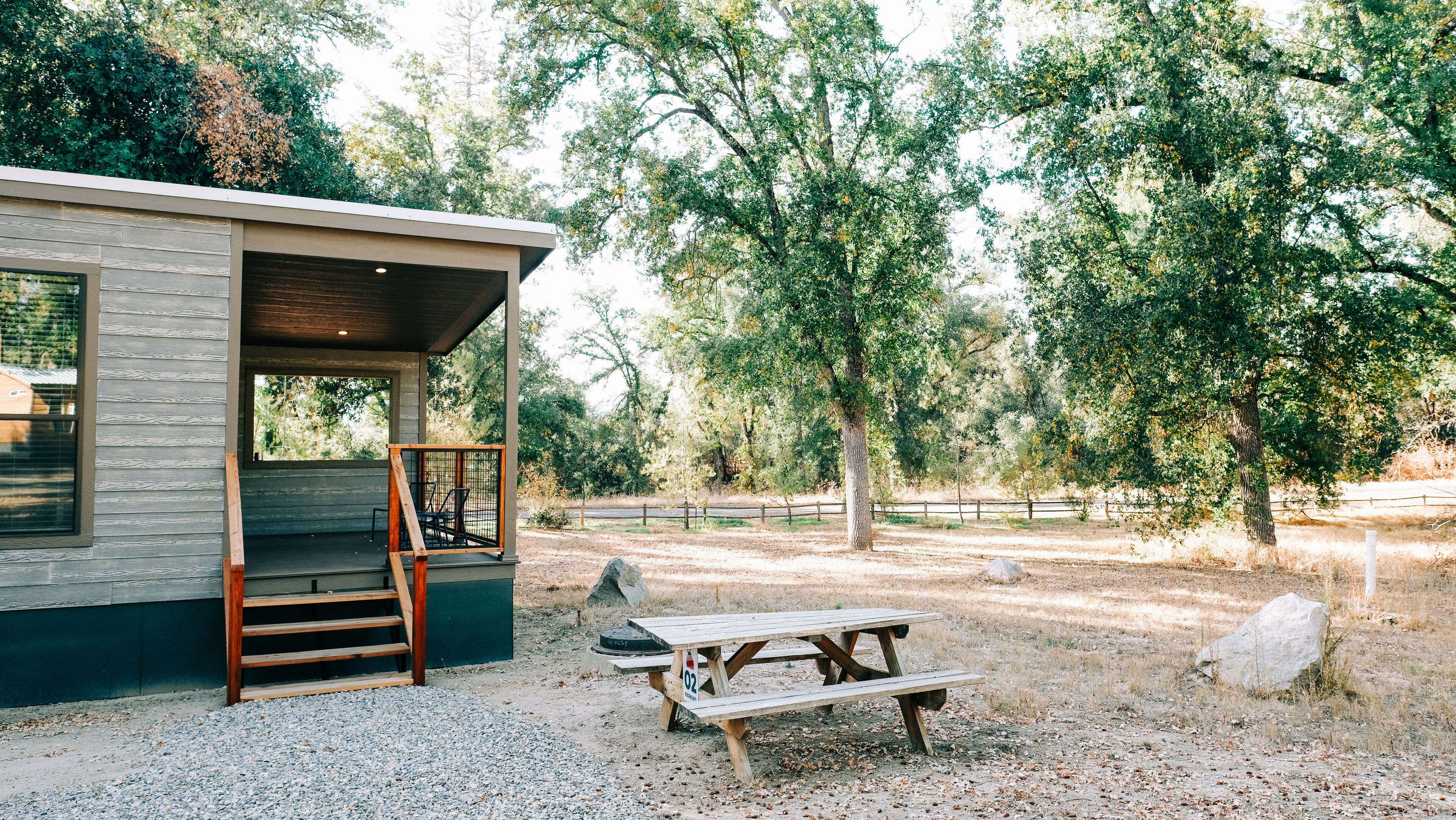A cabin with a porch and a picnic table in a wooded area.