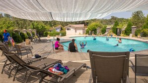 Un área de piscina con sillones de descanso y una sombrilla.
