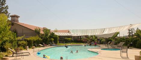 Un área de piscina con sillas de descanso y una sección techada.