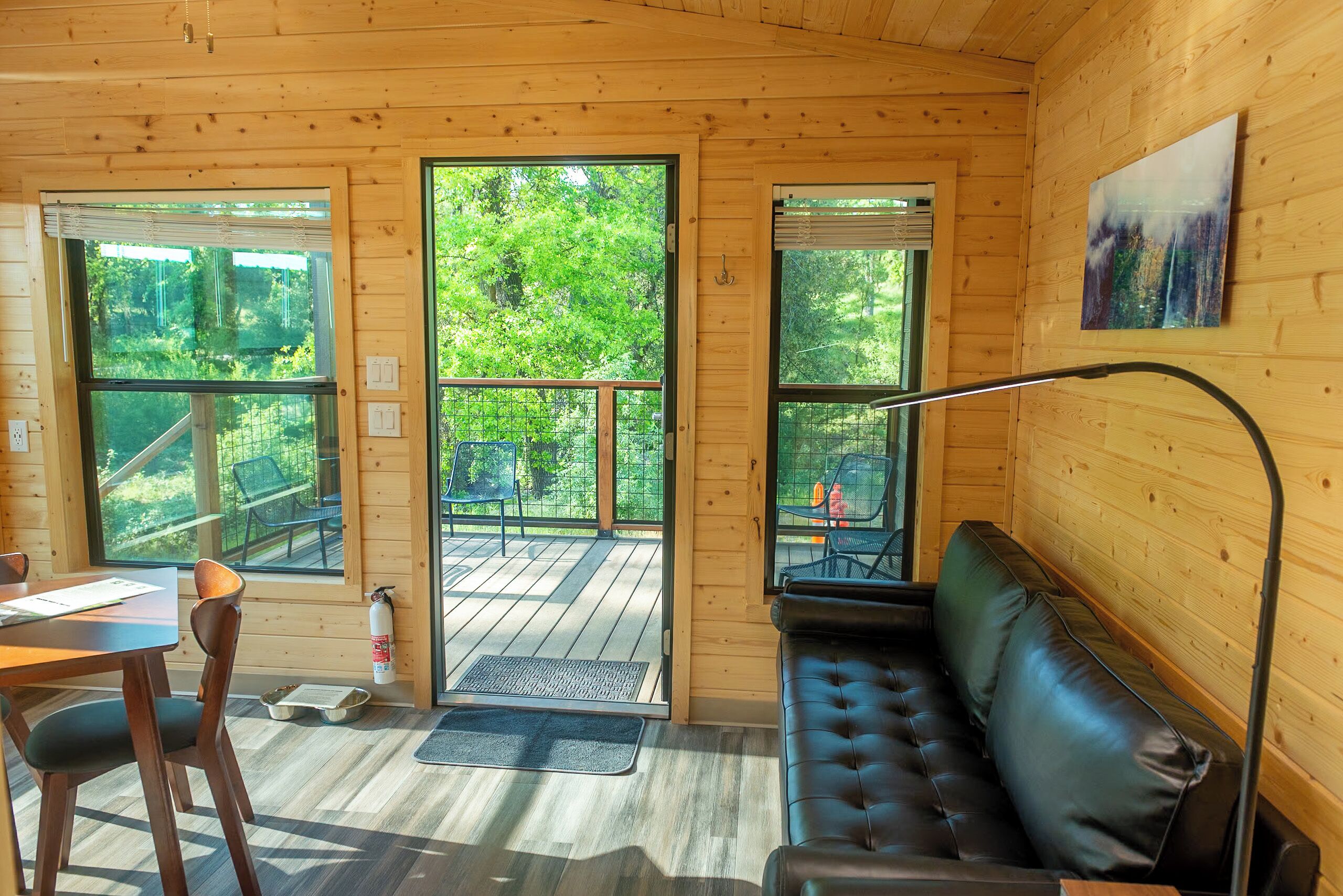 Ein Holzblockhaus-Innenraum mit Essbereich, einer Couch und großen Fenstern mit Blick auf den Wald.