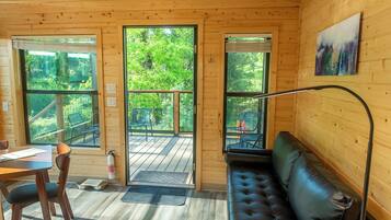 Ein Holzblockhaus-Innenraum mit Essbereich, einer Couch und großen Fenstern mit Blick auf den Wald.