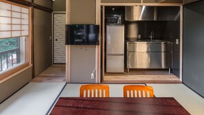 Cocina compacta con microondas, refrigerador y lavamanos. Zona de comedor con mesa y sillas.