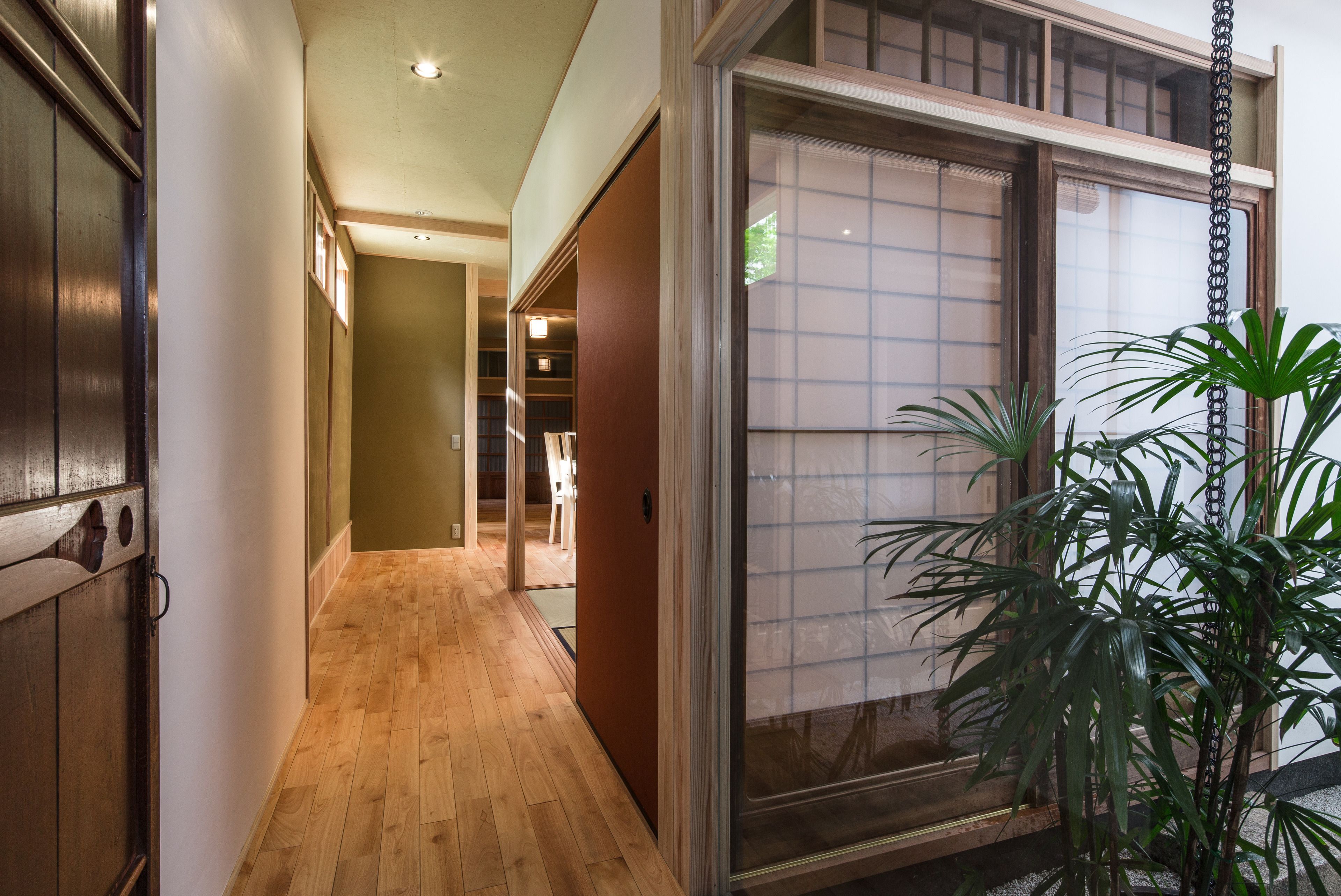 A hallway with wooden flooring and a sliding glass door.