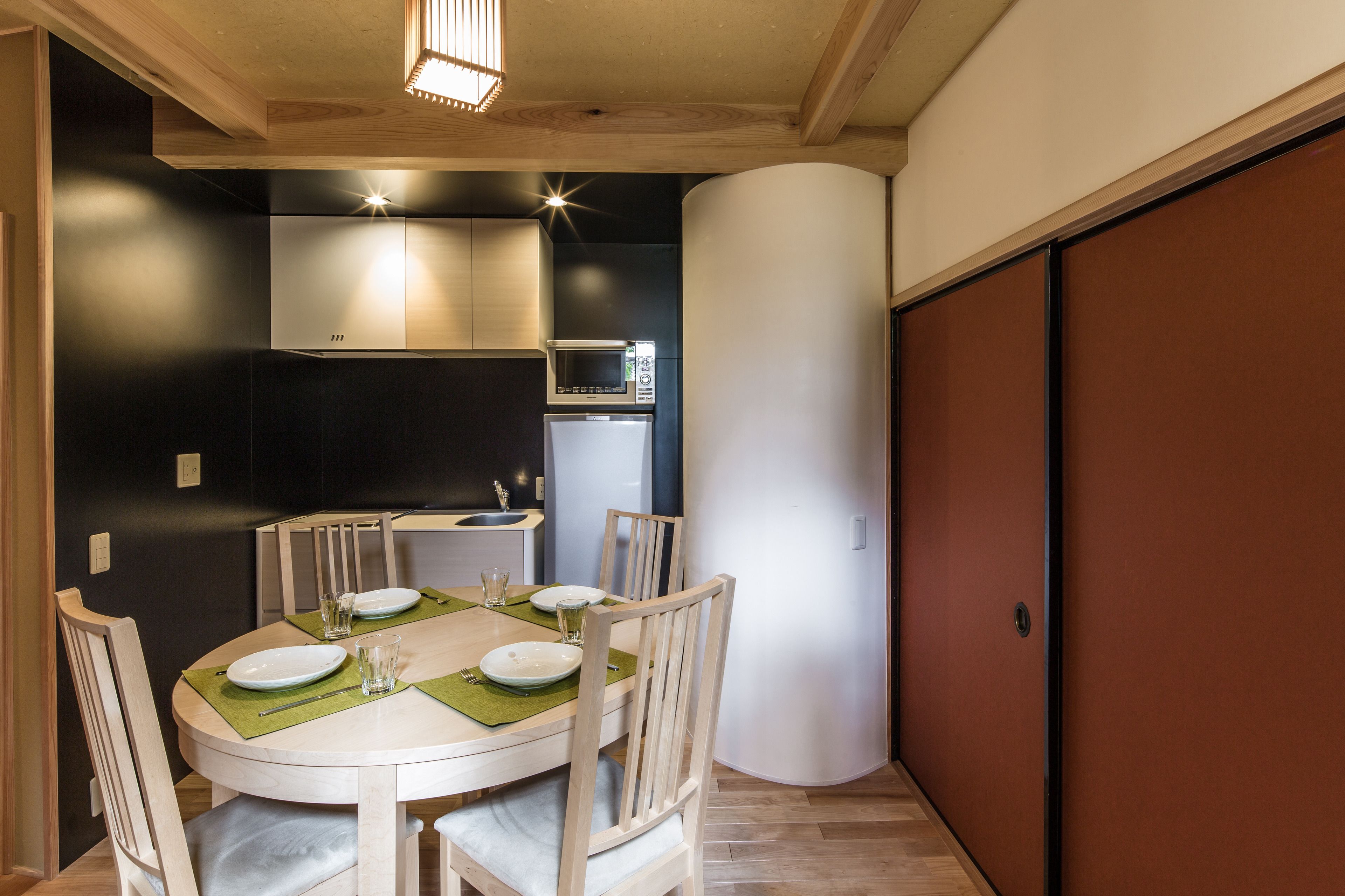 A dining area with a round table set for four, surrounded by wooden chairs.