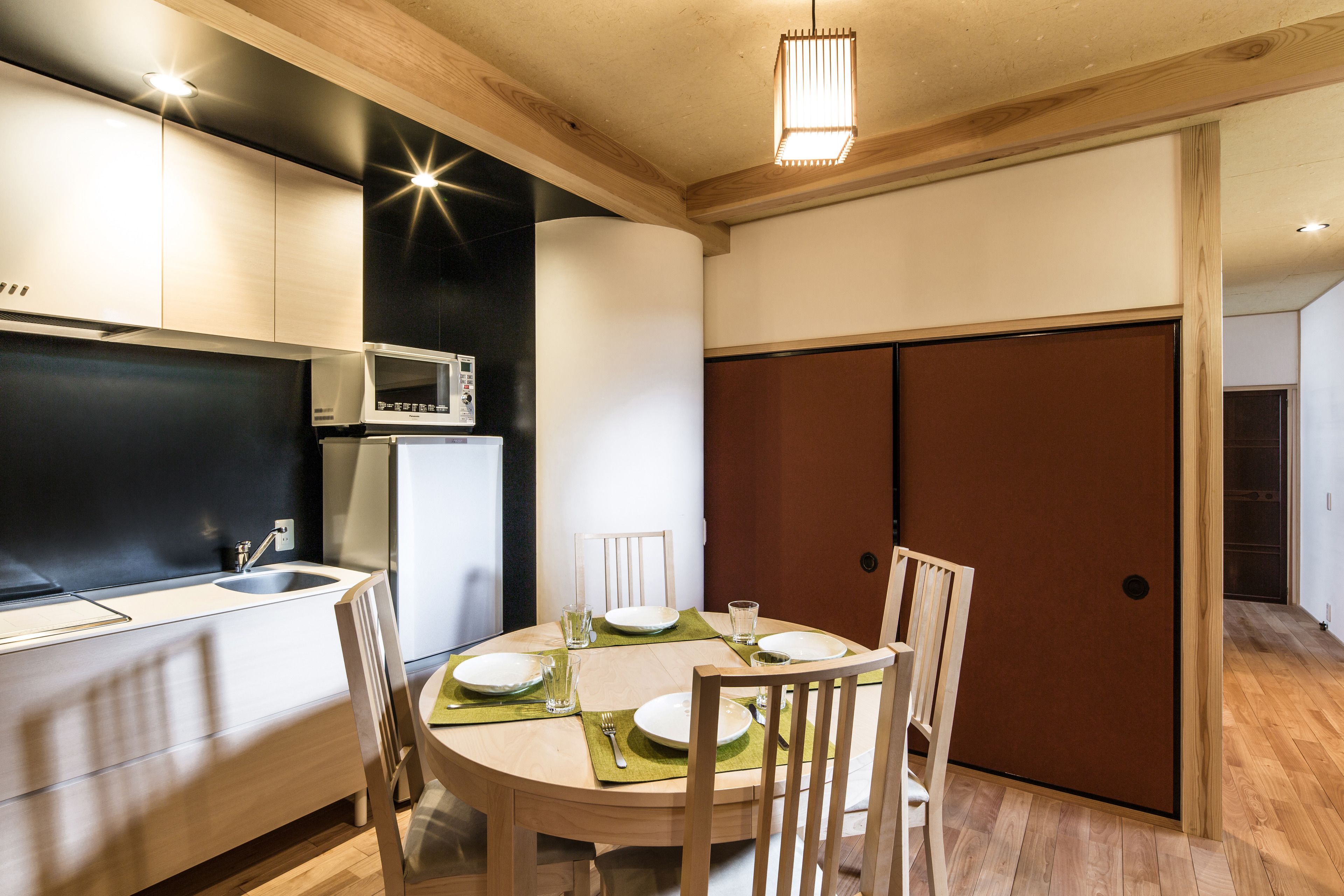 A modern kitchen with a dining area, featuring a microwave, sink, and wooden cabinets.