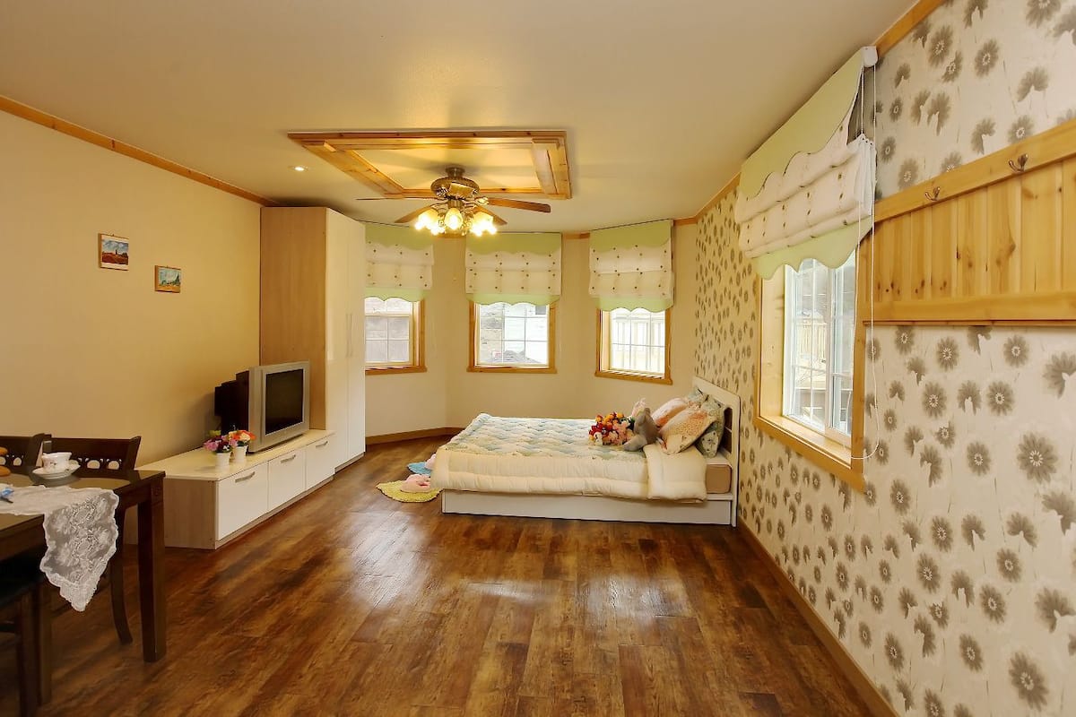 Une chambre à coucher comprenant un lit, un bureau, un téléviseur et un ventilateur de plafond.