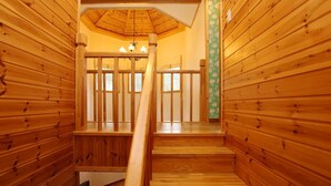 Una escalera de madera con barandilla que conduce a un cuarto con techo de madera y un candelabro.