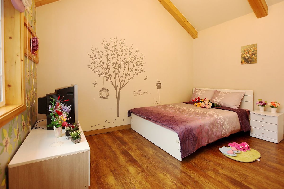 Une chambre à coucher comprenant un lit, des tables de chevet, un bureau et un motif décoratif représentant un arbre sur un mur.
