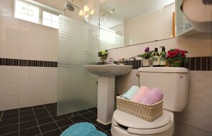 Un bagno moderno con cabina doccia in vetro, lavabo bianco e water con cesto di asciugamani.