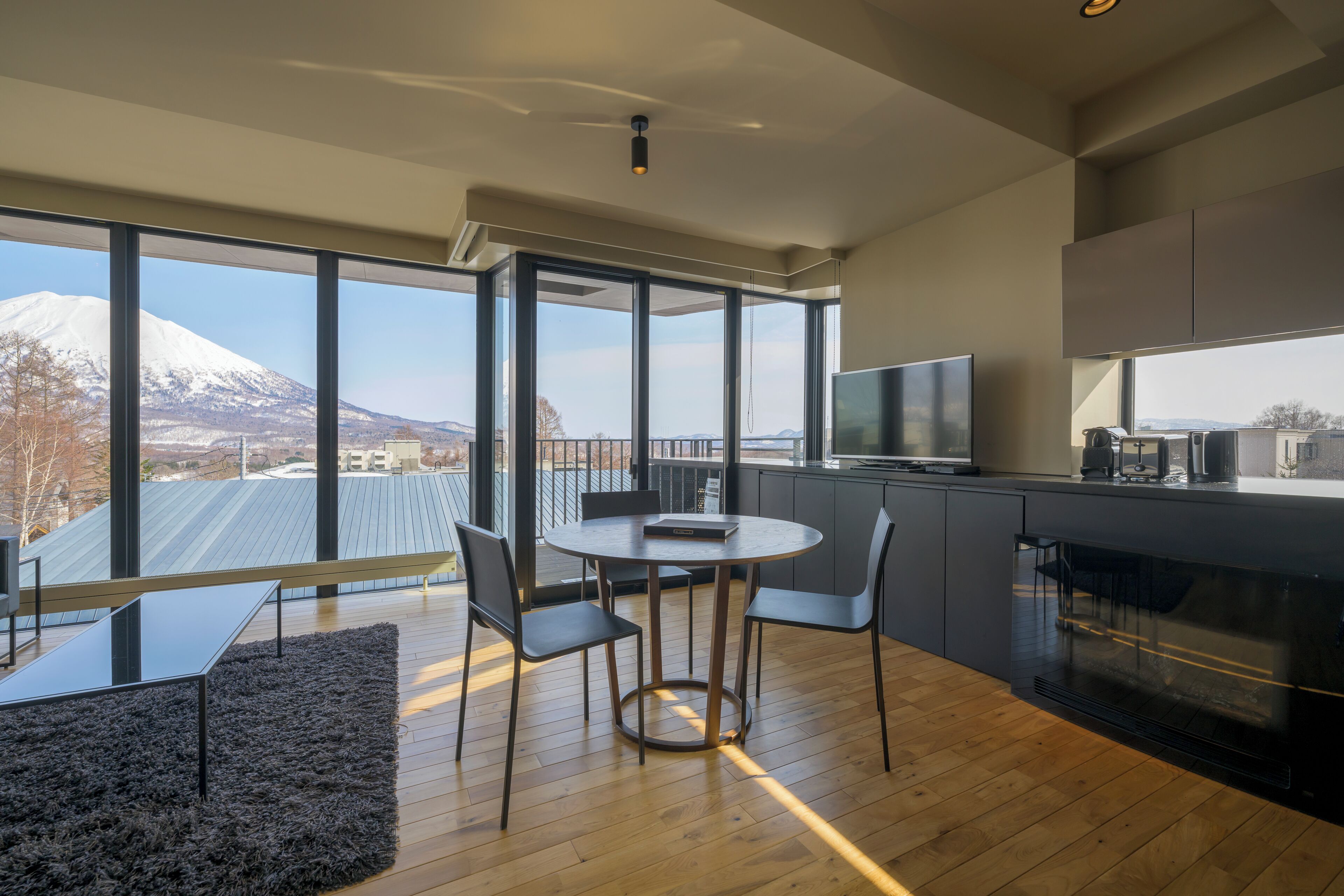 Una cocina moderna con ventanas amplias, un comedor con mesa redonda y vistas a la montaña.
