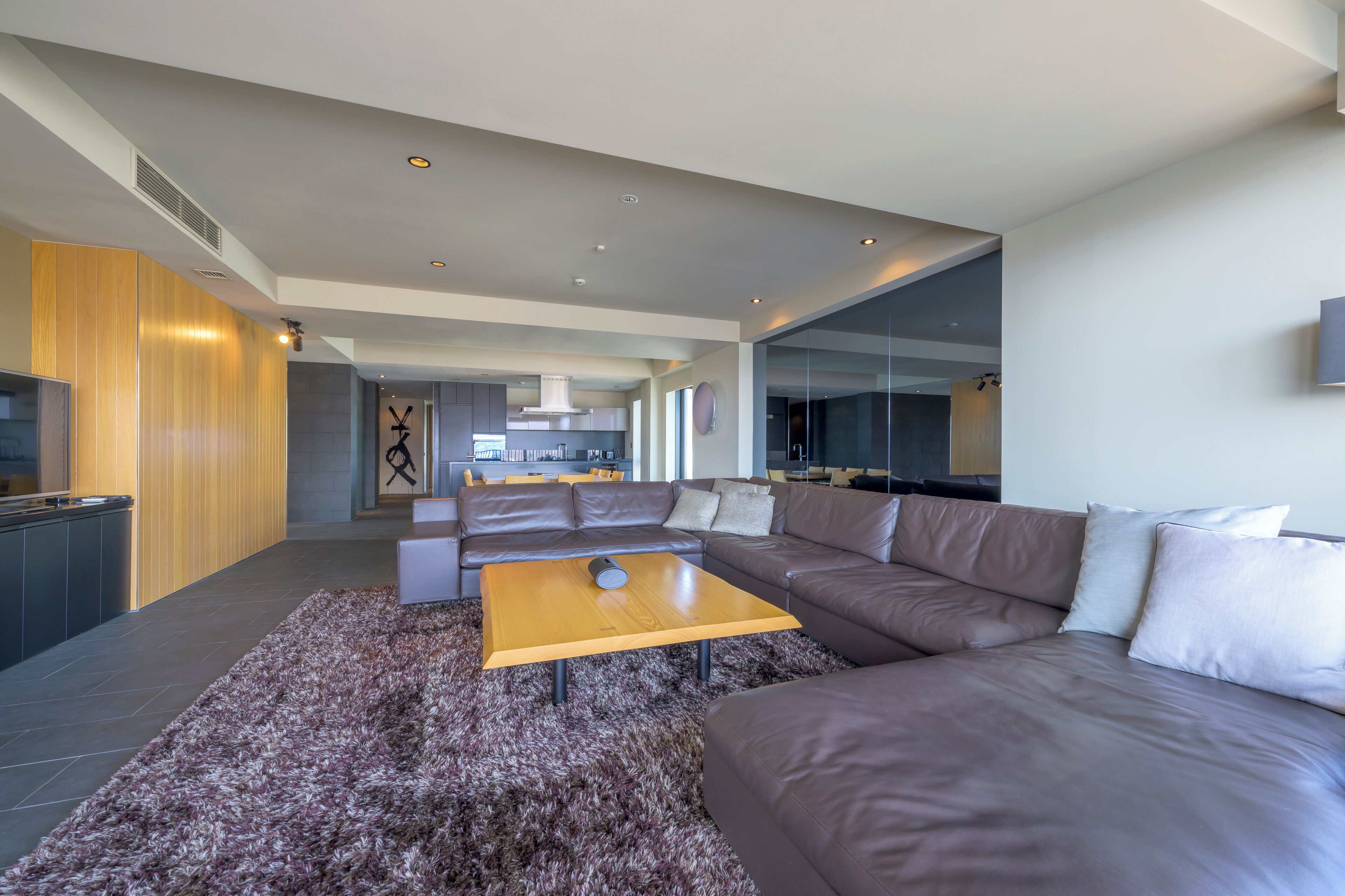 A modern living room with a sectional sofa, a wooden coffee table, and a shaggy rug.