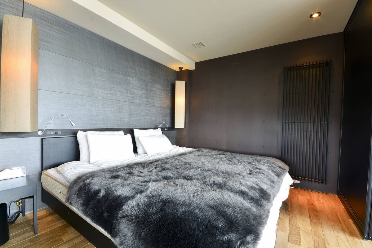 Un dormitorio moderno con una cama grande, una mesita de noche y una lámpara fijada a la pared.