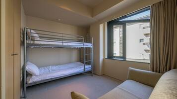 A room with a bunk bed, a sofa, and a window with curtains.