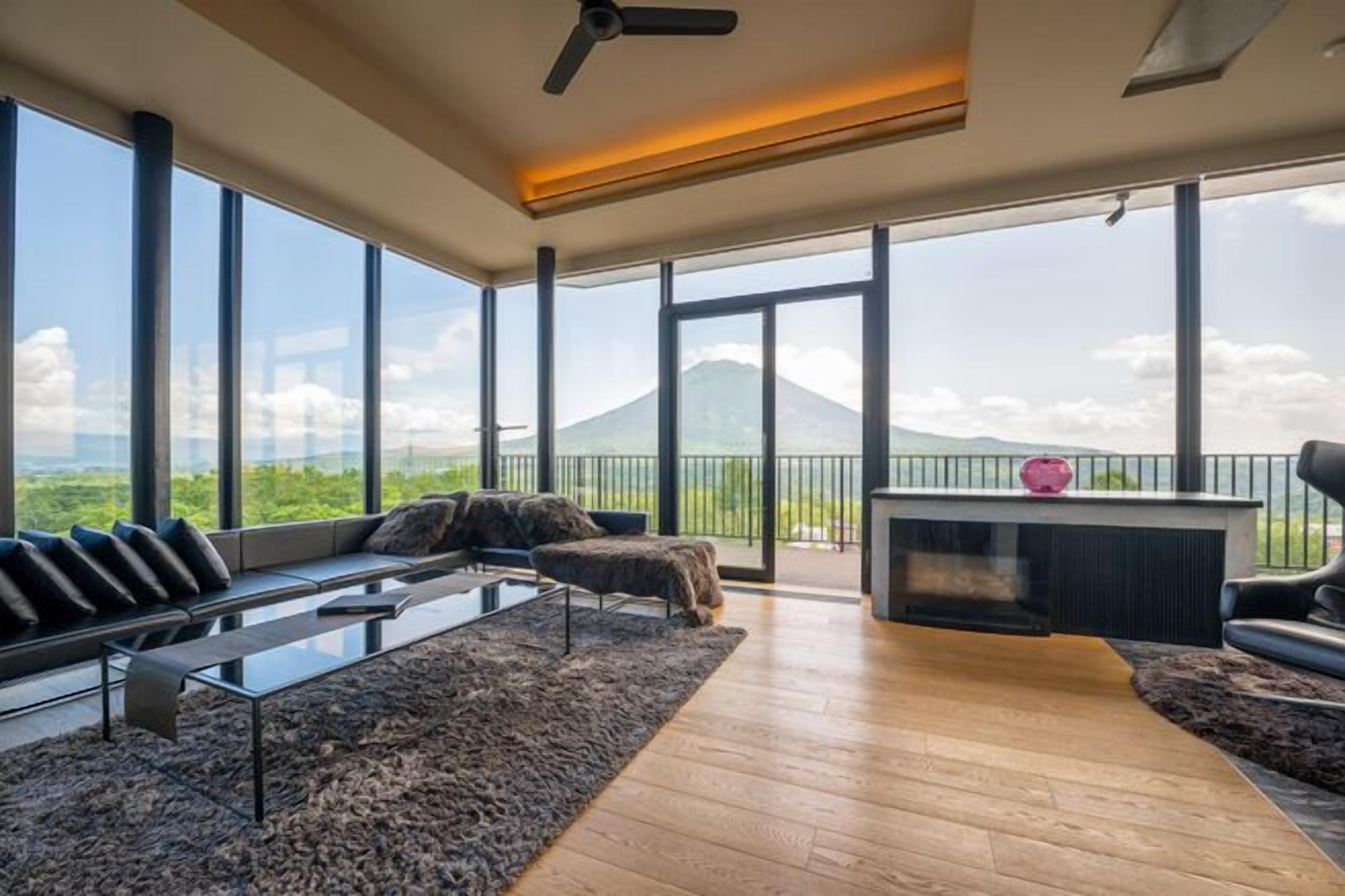 A modern living room with a sofa, coffee table, and a view of a mountain.