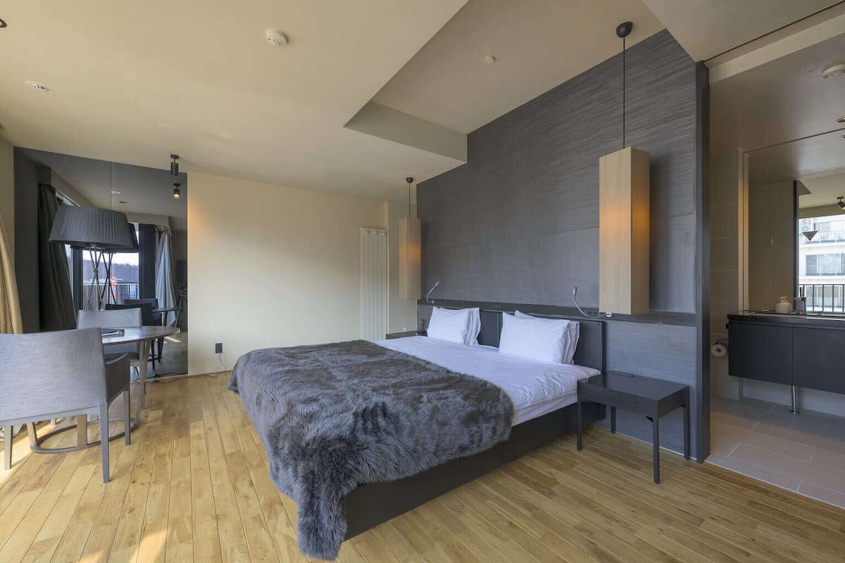 Una habitación de hotel moderna con una cama grande, un escritorio y un espejo.