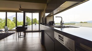 A modern kitchen with a large island, a built-in dishwasher, and a view of a mountain. - MUSE Niseko (Kutchan)