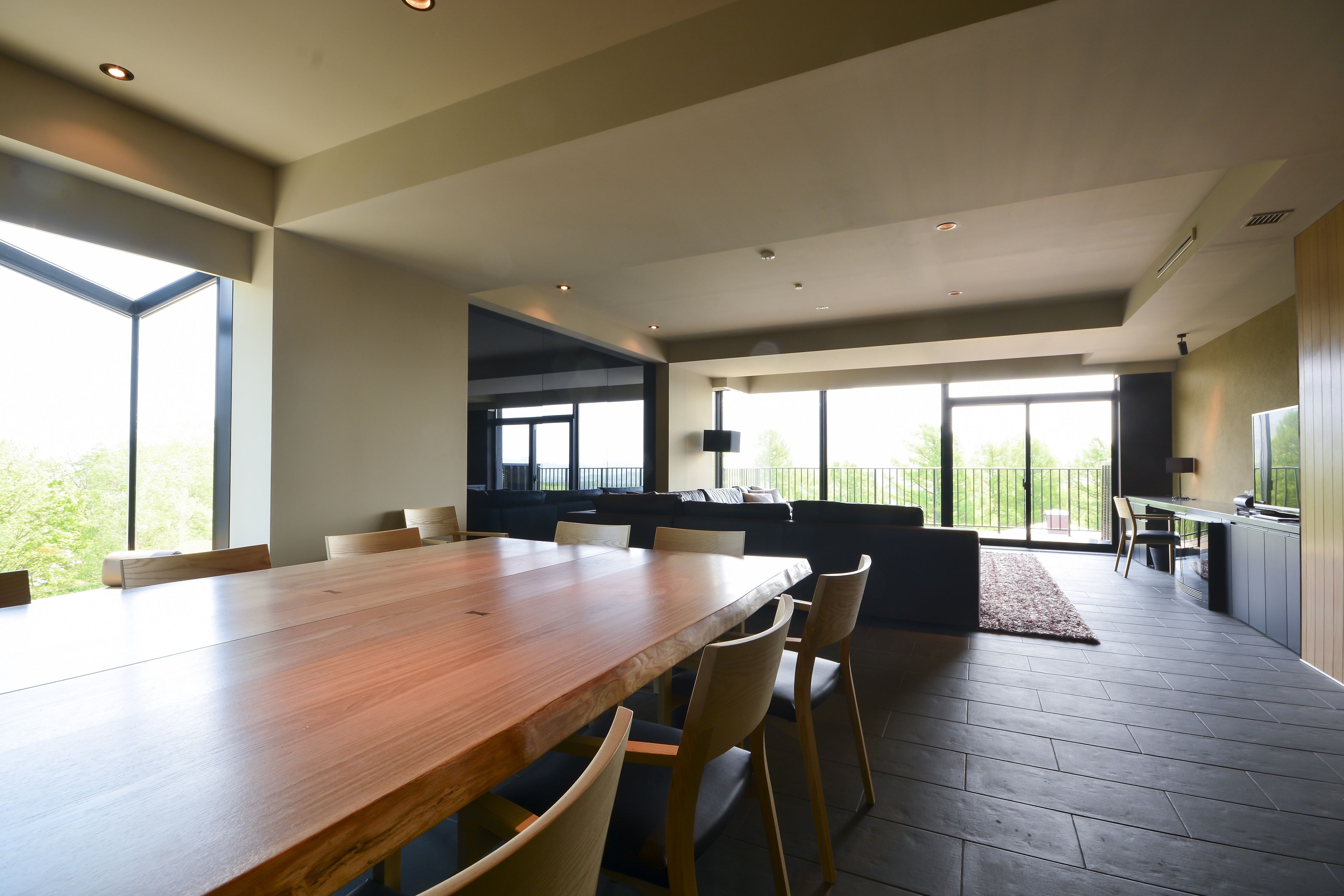 A modern kitchen with a large wooden table, built-in appliances, and a view to the outdoors.