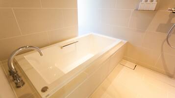 A modern bathroom with a bathtub, a shower, and a toilet.