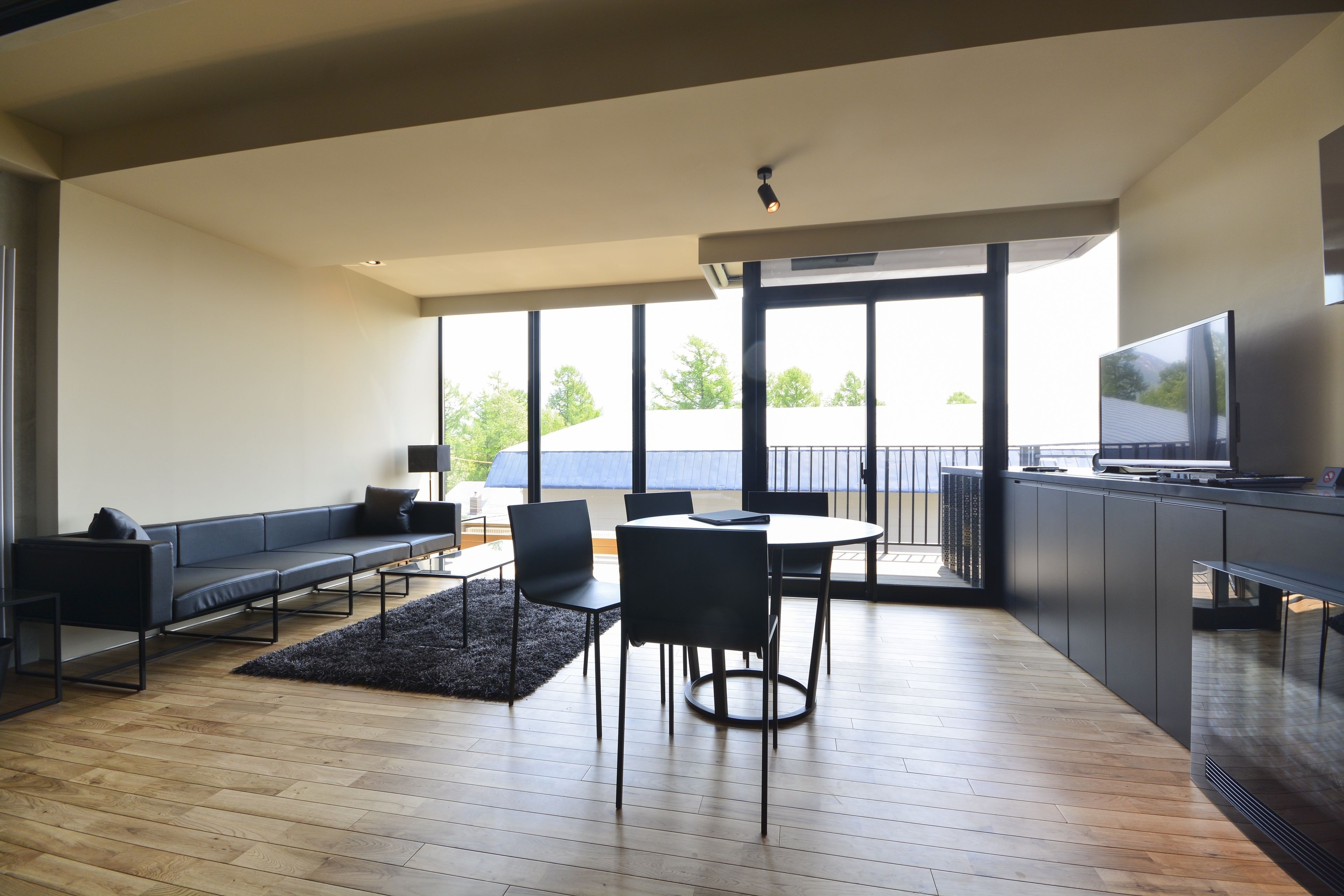 Una sala de estar moderna con un sofá, sillas, una mesa de comedor y un televisor.