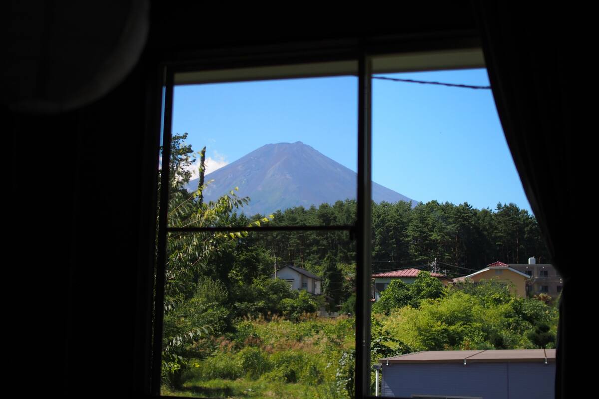 A window view of a mountain, likely a volcano, with a clear sky.