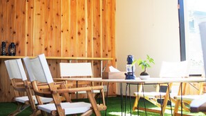 A room with wooden panel walls, a clock, and a table with chairs. - Kikkake Green and Mt.Fuji - Hostel (Fujiyoshida)