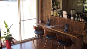 A bar area with wooden furniture, a potted plant, and a view through a glass door. - Kikkake Green and Mt.Fuji - Hostel (Fujiyoshida)