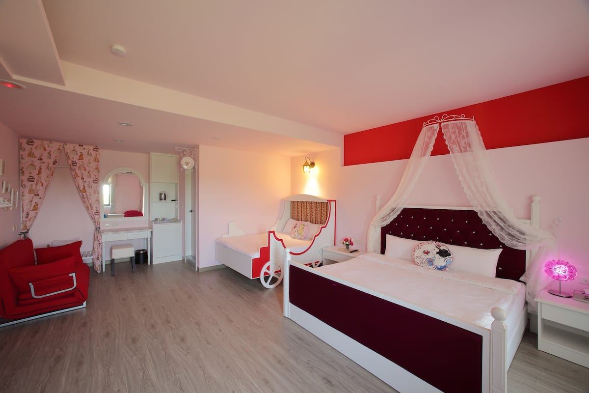 A bedroom with a bed, a desk, a chair, and a vanity.
