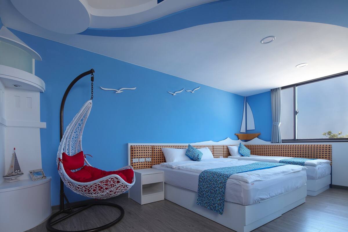A modern bedroom with a hanging chair, a bed with a wooden headboard, and a sailboat decoration on the wall.