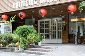 Entrada de un hostal con faroles chinos tradicionales, fachada de madera y un letrero.