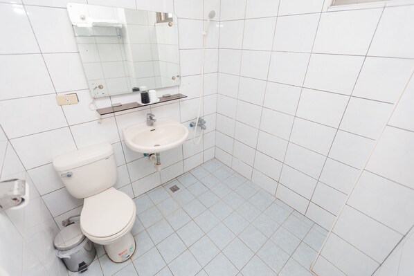 Un baño pequeño y limpio con azulejos blancos, inodoro, lavabo y espejo.
