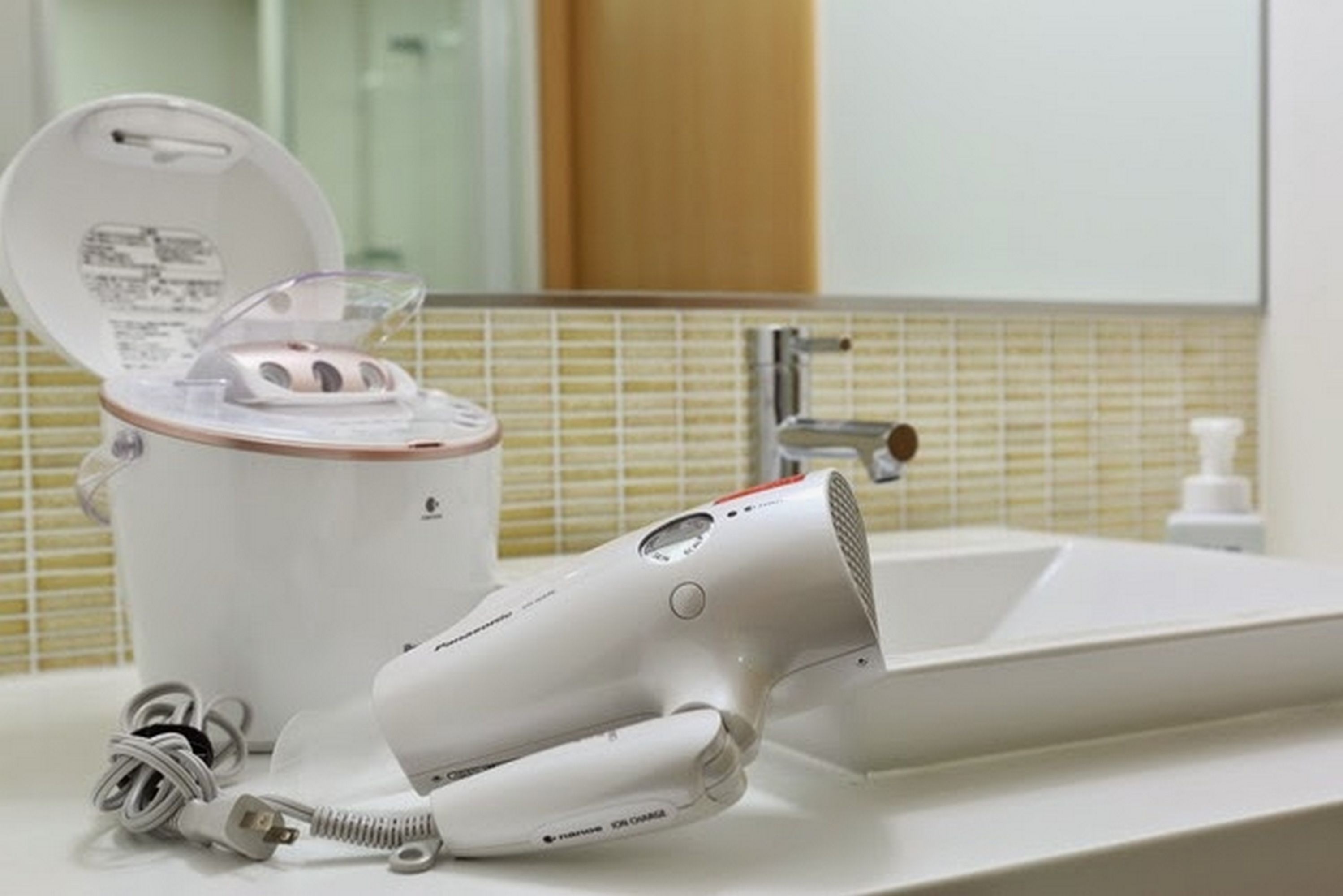 A bathroom with a white sink, a mirror, and a hairdryer on the counter.