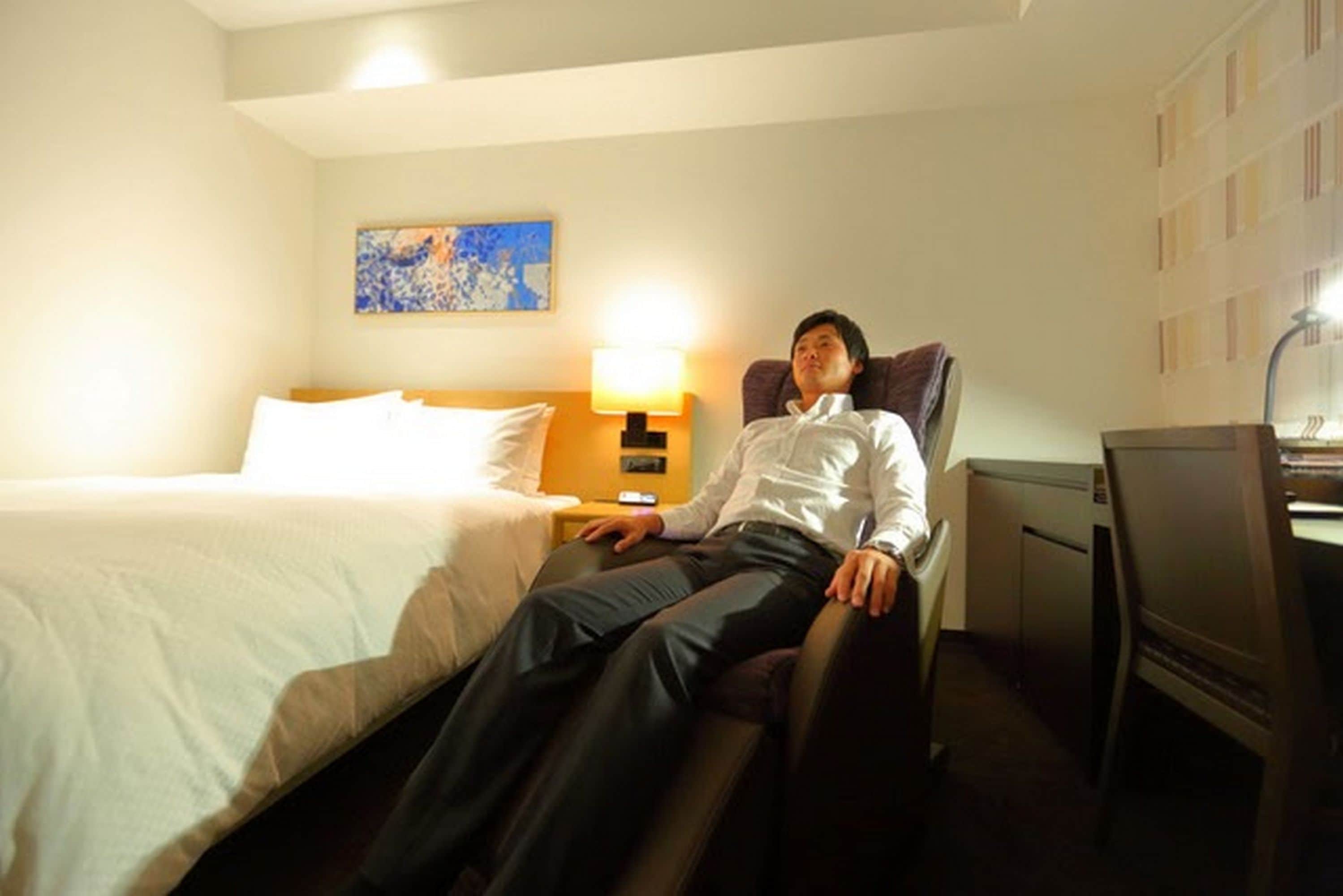 A hotel room with a bed, a desk, and a chair.