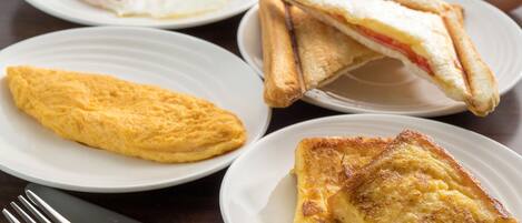 A breakfast setting with plates of toast, an omelet, and a fried egg.