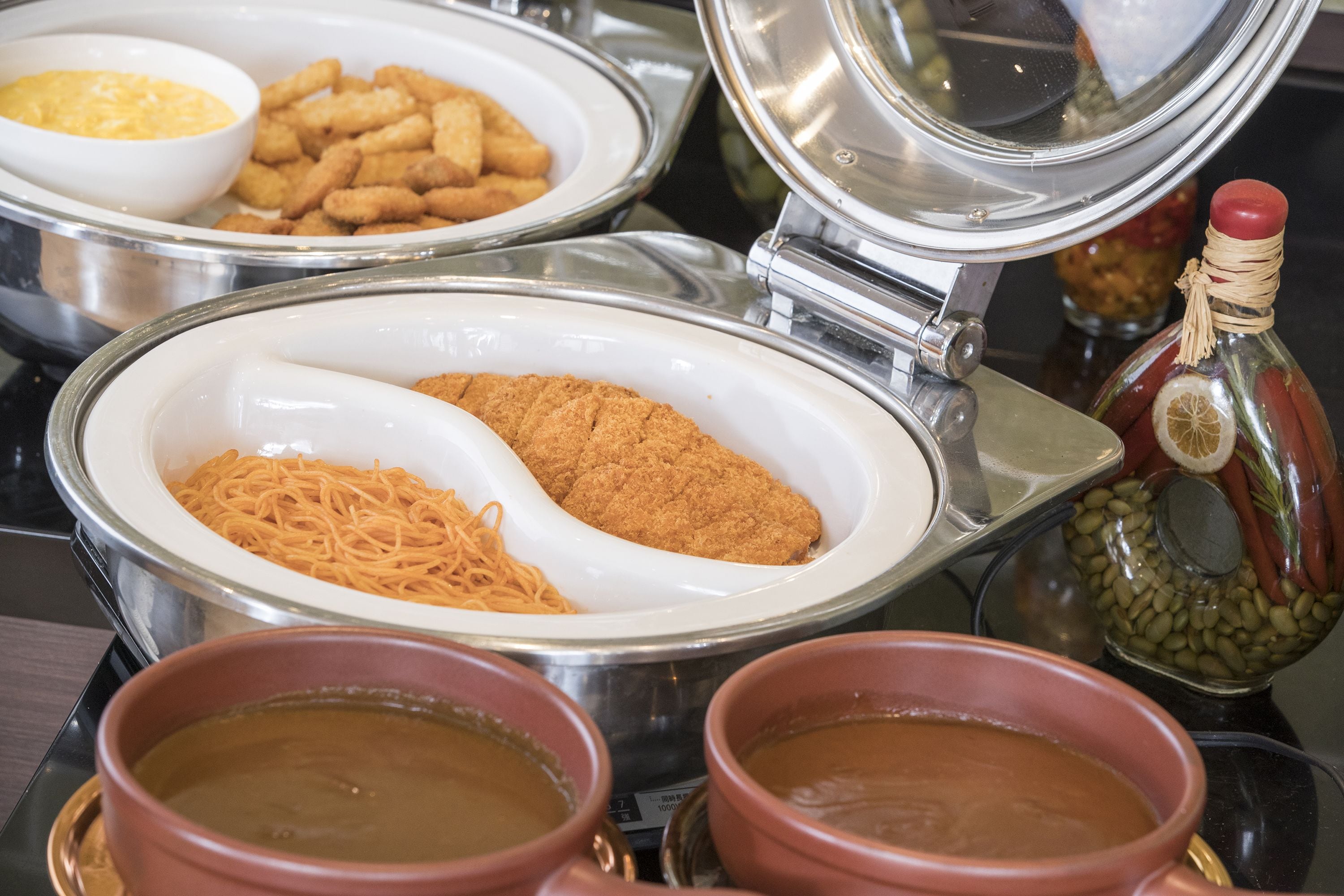 A buffet setup with various dishes including noodles, fried items, and soups.