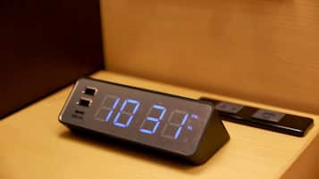 Um relógio digital em cima de uma mesa de cabeceira de madeira mostrando as 22h34.
