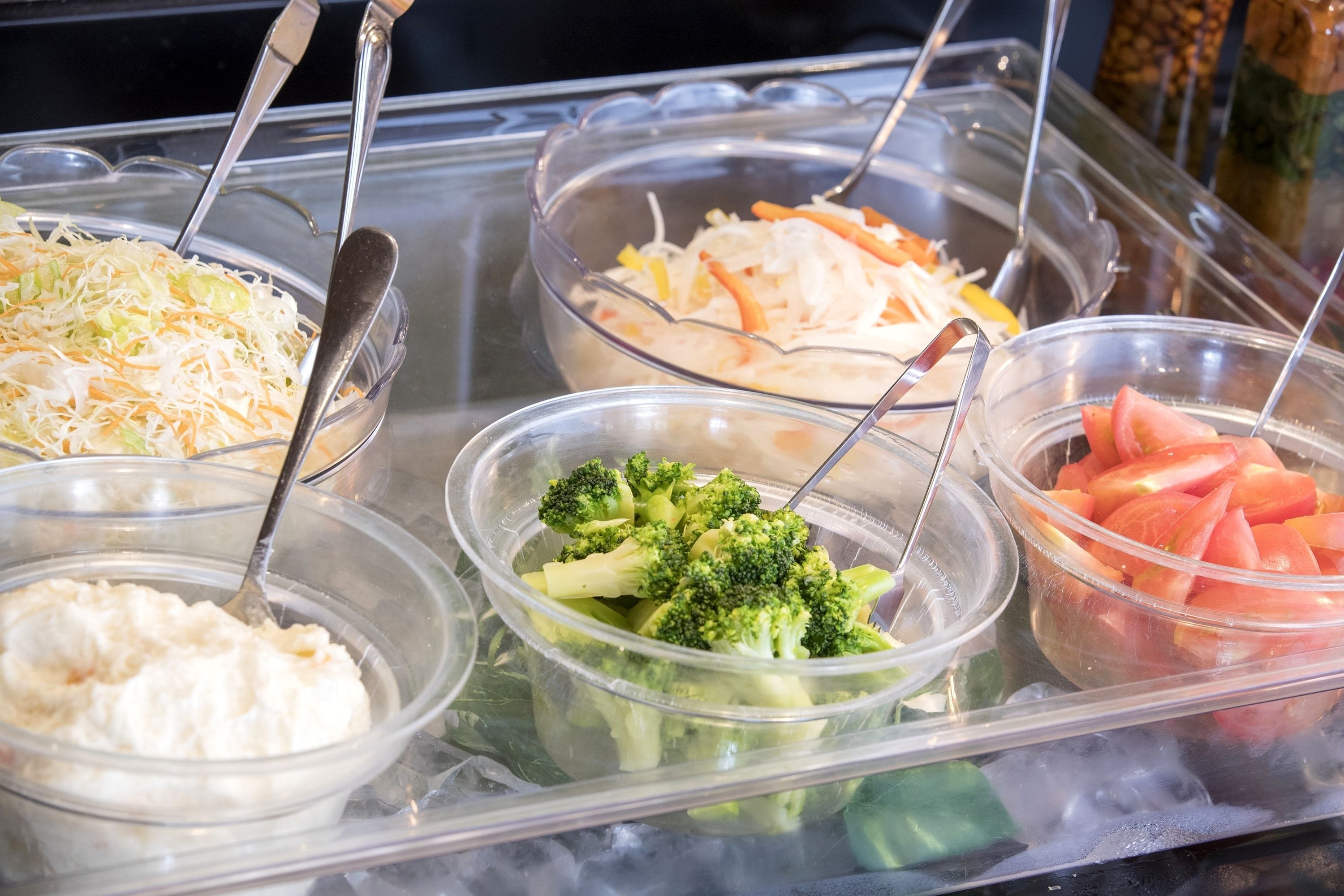 A buffet with various food items including coleslaw, broccoli, and watermelon.