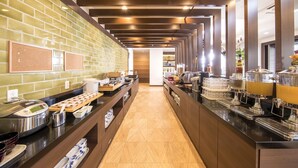 Un espace buffet proposant différents postes de restauration, avec un choix de plats chauds et froids, ainsi qu’une variété d’ustensiles de service.