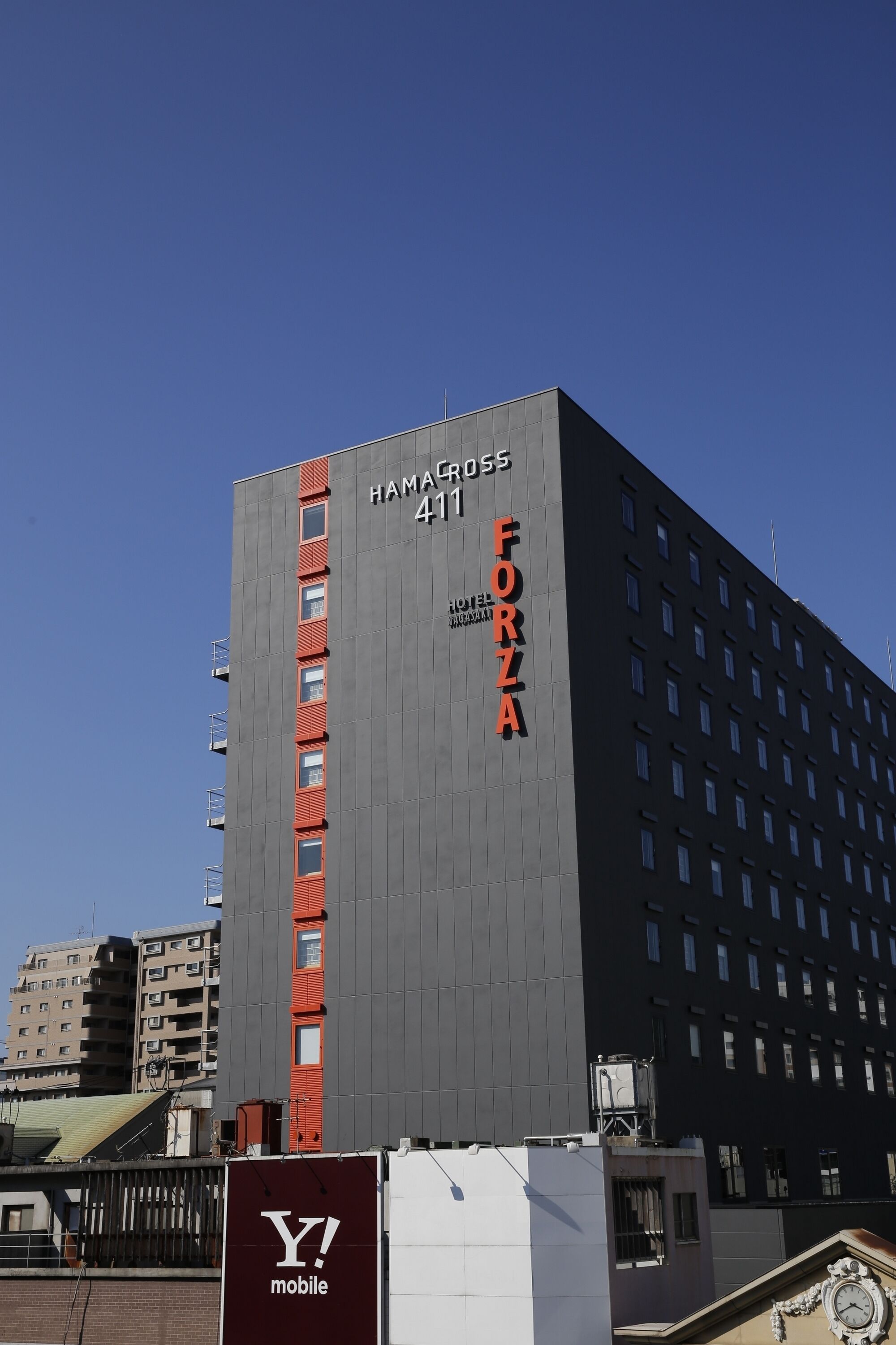 A modern hotel building with the name "HAMACROSS 411" and "FORZA" on its facade.