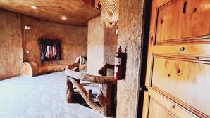 Um quarto rústico com teto de madeira, uma grande porta de madeira e piso de azulejos.