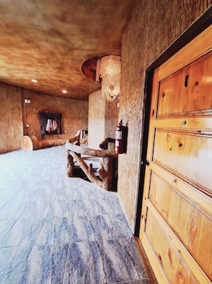 A rustic room with a wooden ceiling, a large wooden door, and a tiled floor. - Timberland and Fruit Resort (Suan Phueng)