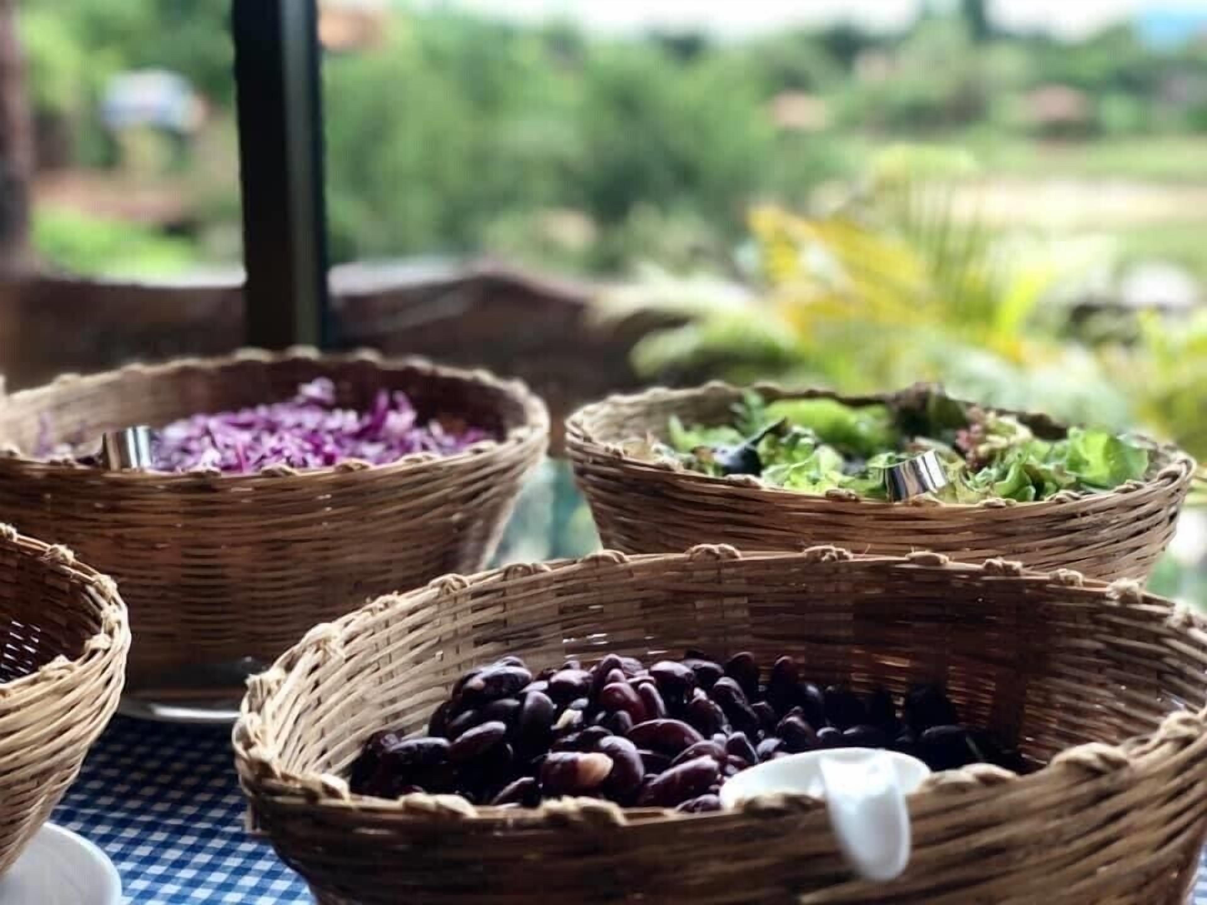 A table with four woven baskets containing different types of food.