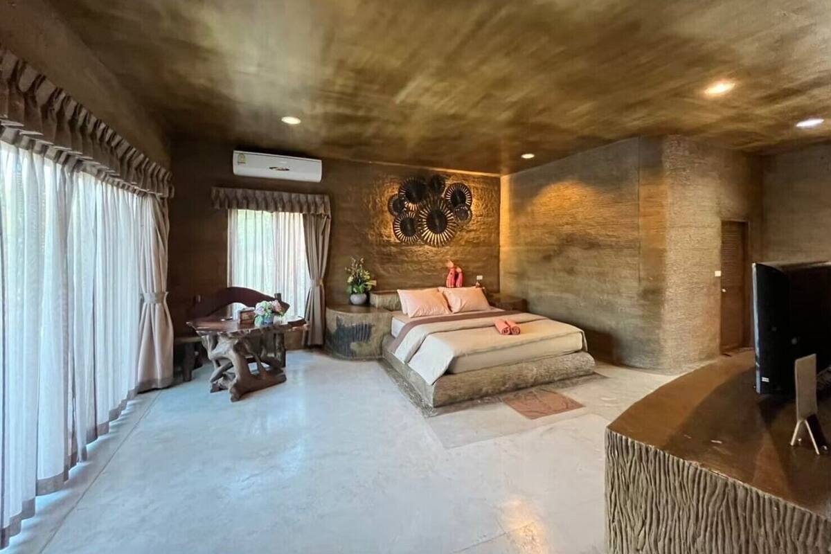 A bedroom with a large bed, a desk, and a television.