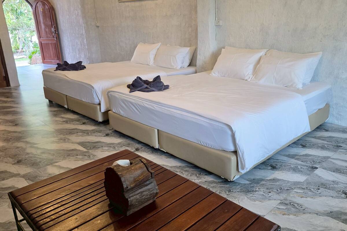 A hotel room with two beds, a wooden bench, and a marble floor.