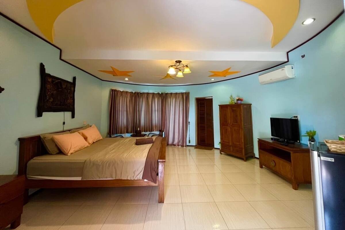 A hotel room with a bed, a TV, a wardrobe, and a ceiling fan.