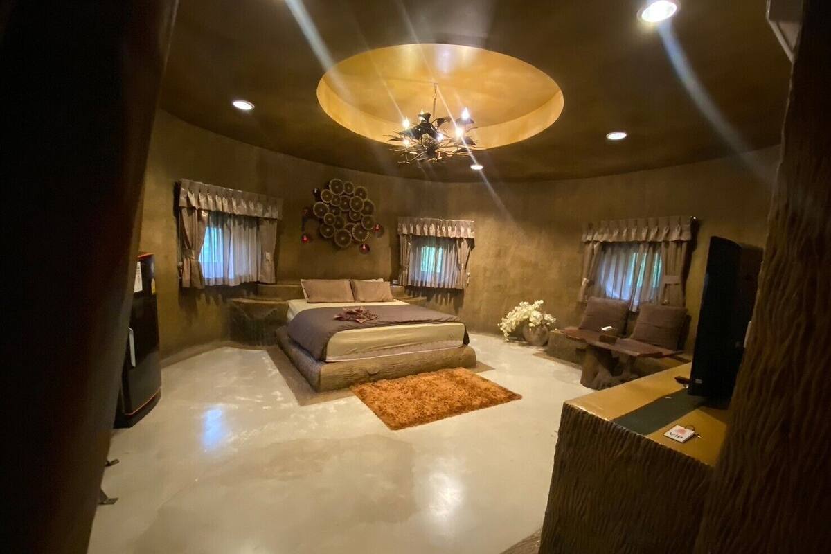 A modern bedroom with a large bed, a desk, and a television.