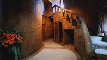 A narrow hallway with a wooden staircase leading to an upper level.